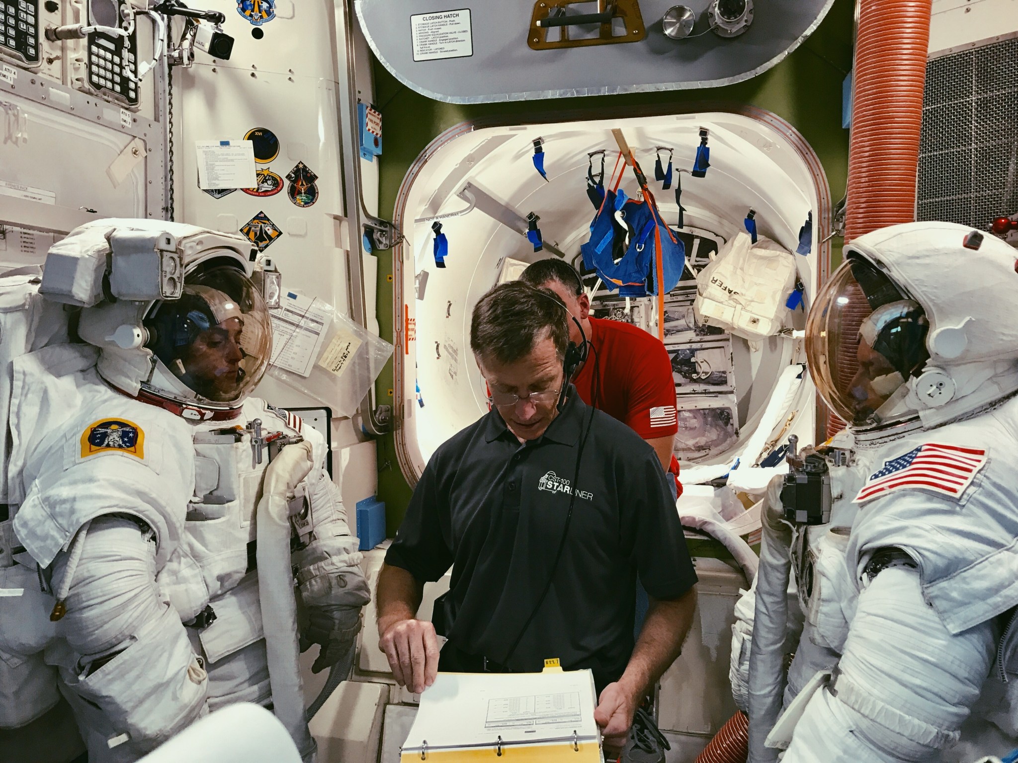 Chris Ferguson, with Boeing, helps Nicole Mann, left, and Mike Fincke, right, both with NASA, train for a spacewalk.