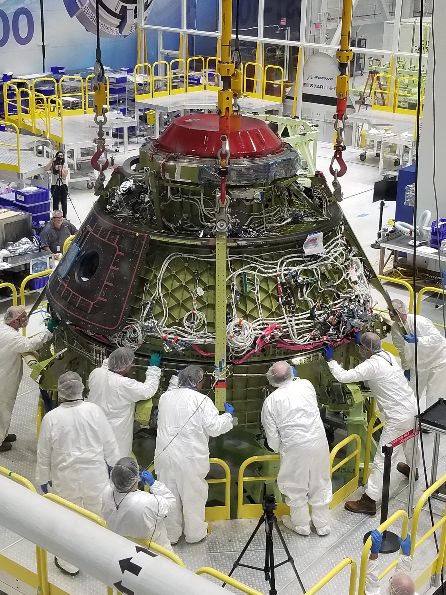Boeing technicians meticulously lower the Starliner upper dome to the lower dome before bolting and sealing the pressure vessel.