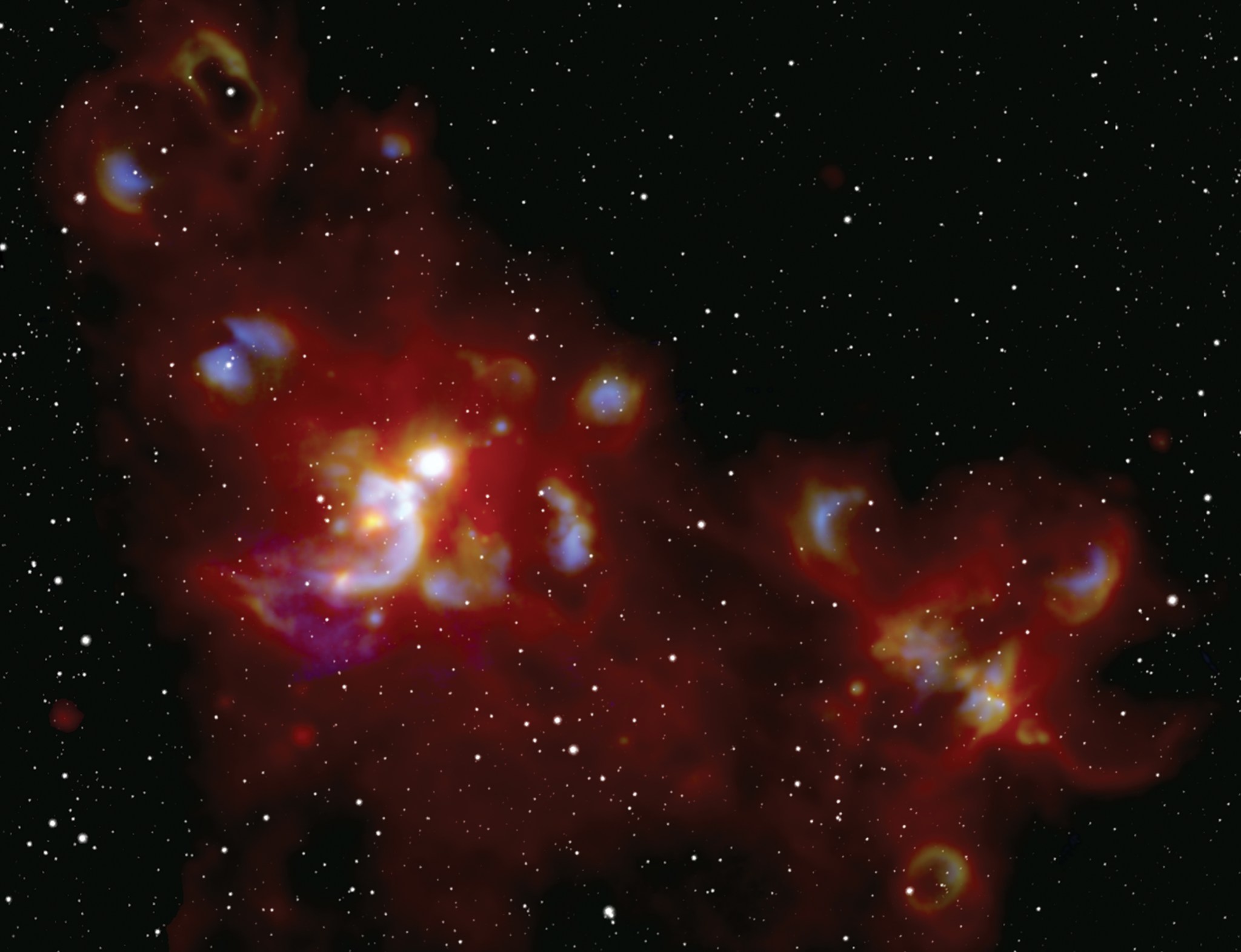 Forming stars glow in orange, purple and blue in front of a black and white star field.