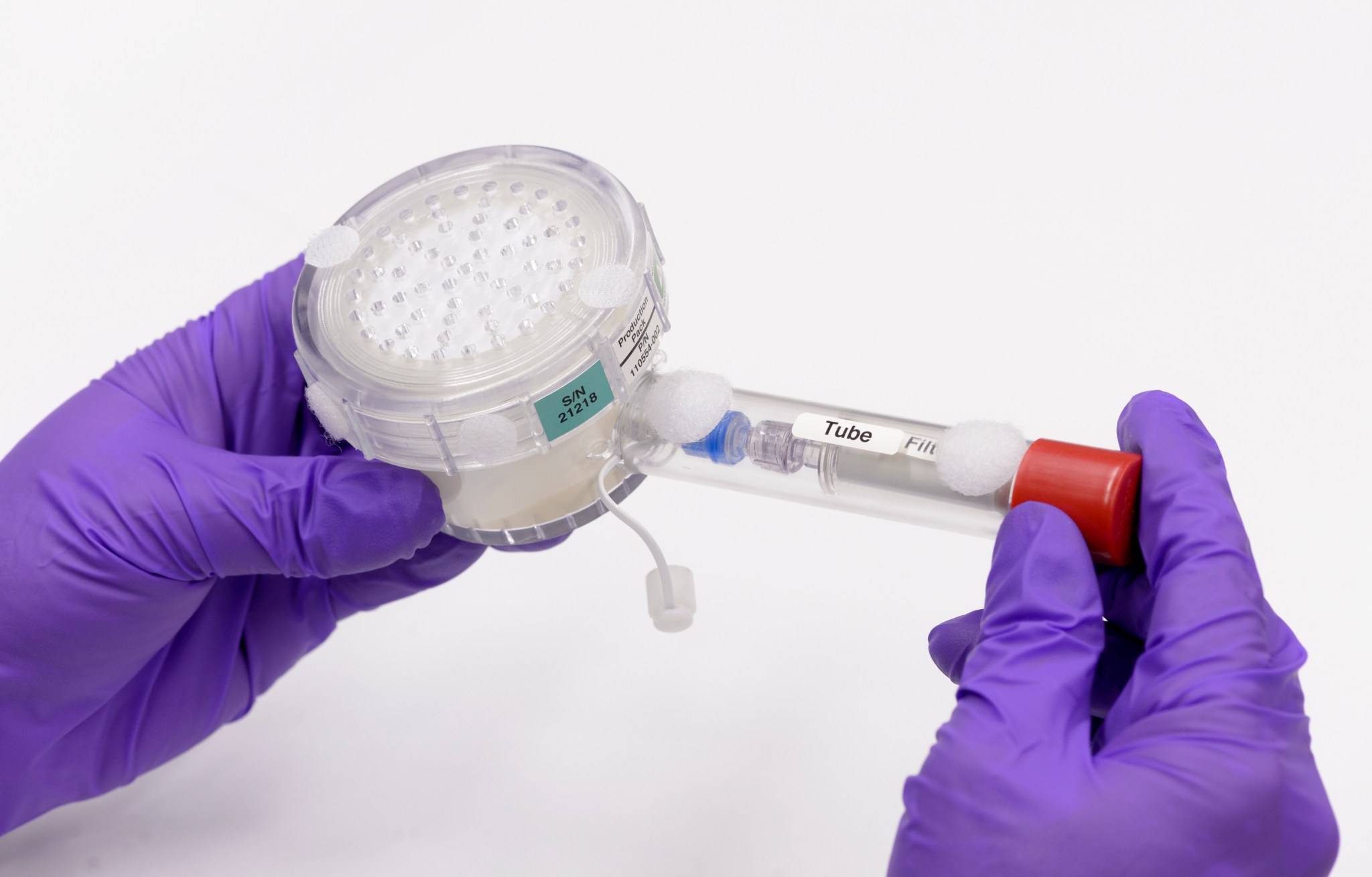 Close up of purple-gloved hands holding a BioNutrients production pack.