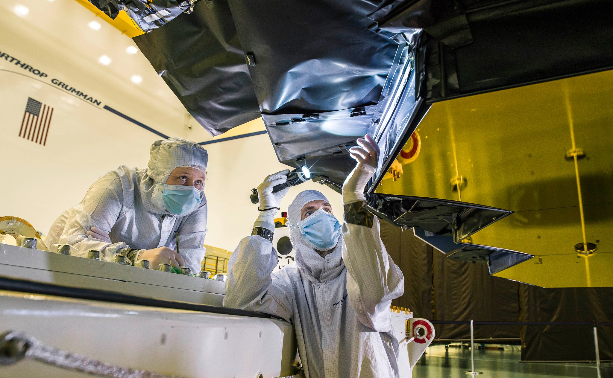 Northrop Grumman blanket technician Ann Meyer, and Ball Aerospace optical engineer Larkin Carey inspect the protective barrier.