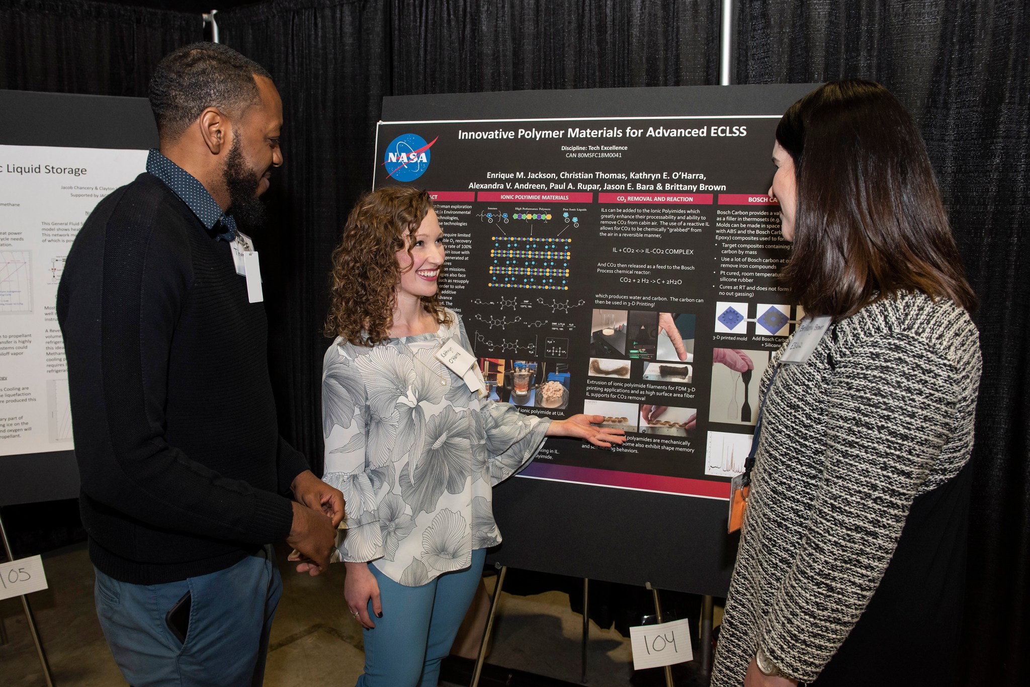 Graduate students Christian Thomas, left, and Kathryn O’Harra, center, discuss their technology poster with Brittany Brown.