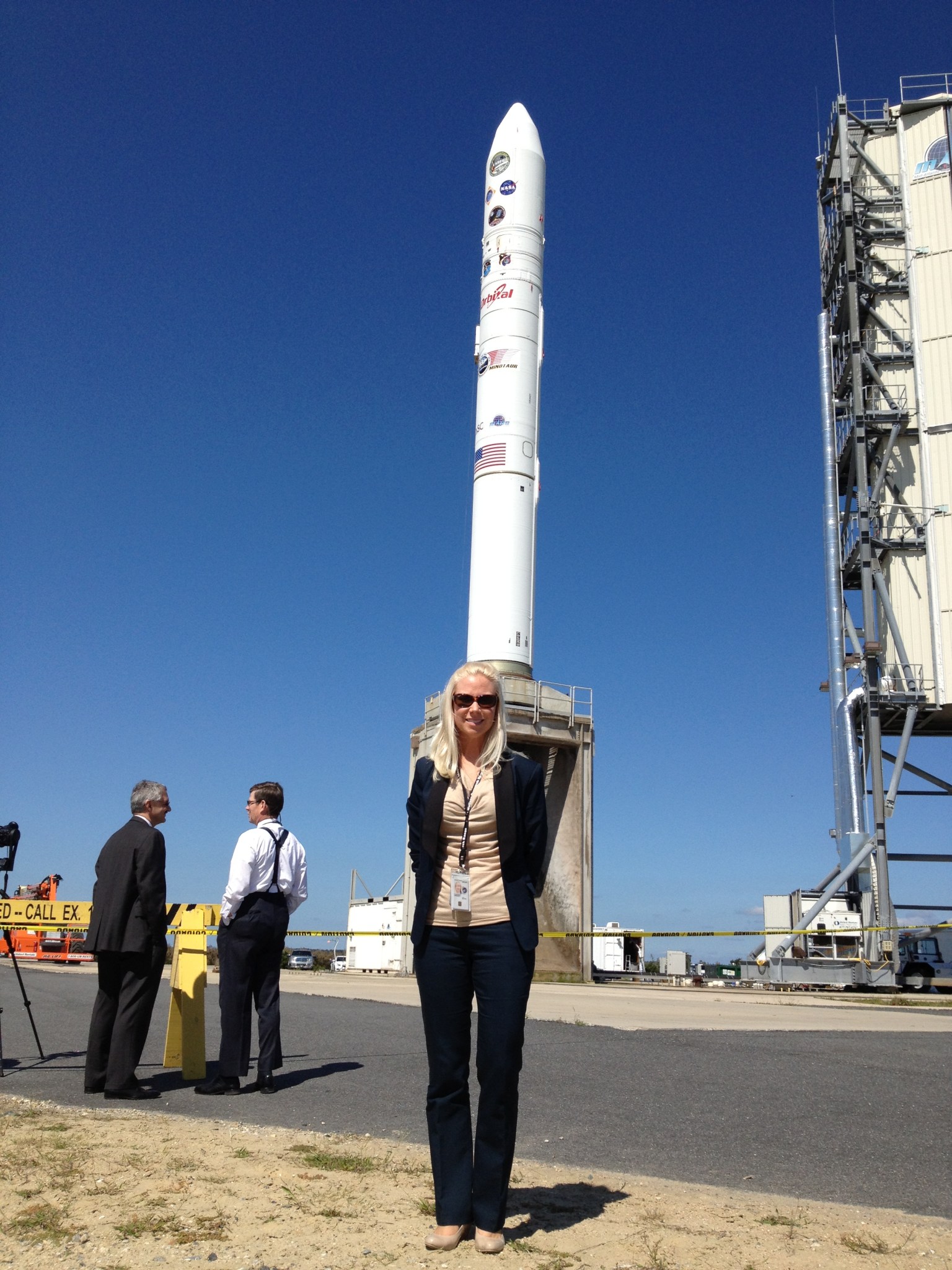 Woman with blonde hair and fair skin stands in front of a rocket