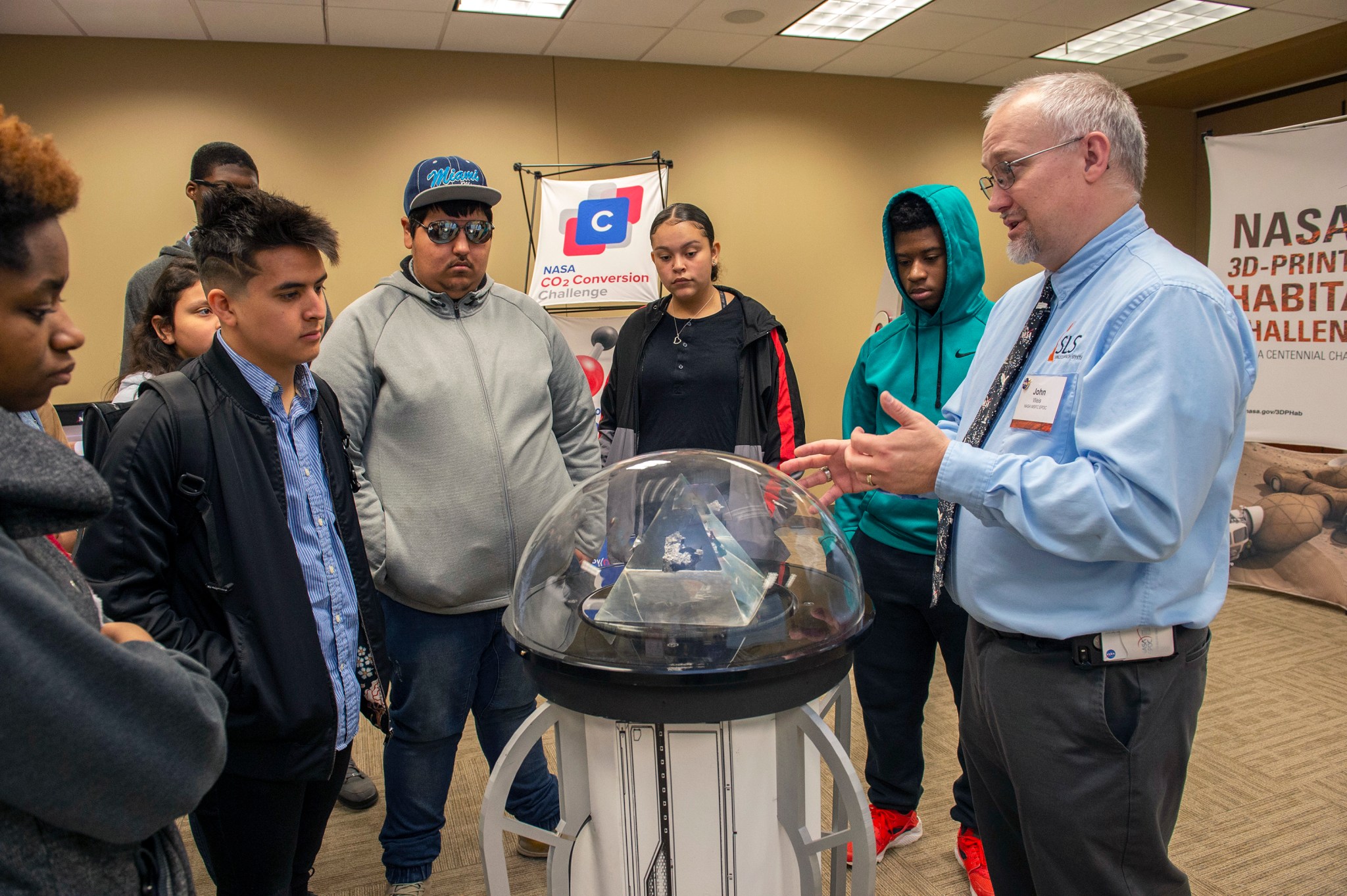 NASA's John Weis, right, offers students a first-hand look at a Moon rock retrieved by the Apollo 15 mission. 