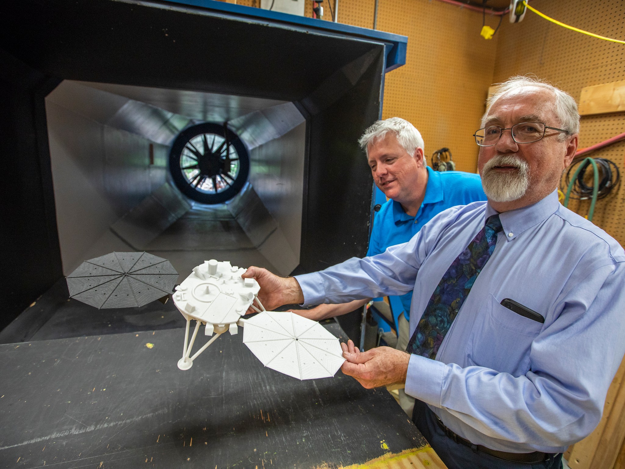 Richard White, right, shows off a model of the Mars InSight lander as Robert Betts, center, looks on.
