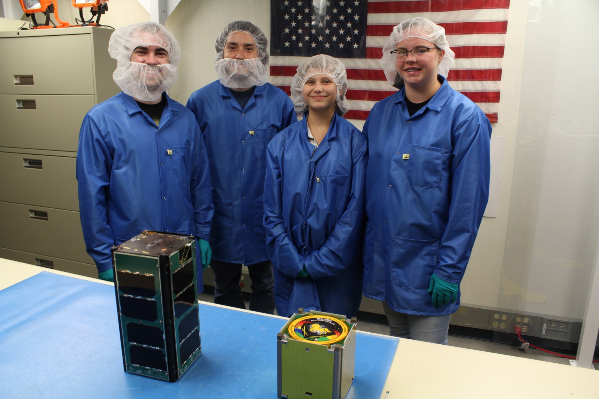 Merritt Island High School students are photographed at the Kennedy Space Center with a cube satellite the students built.