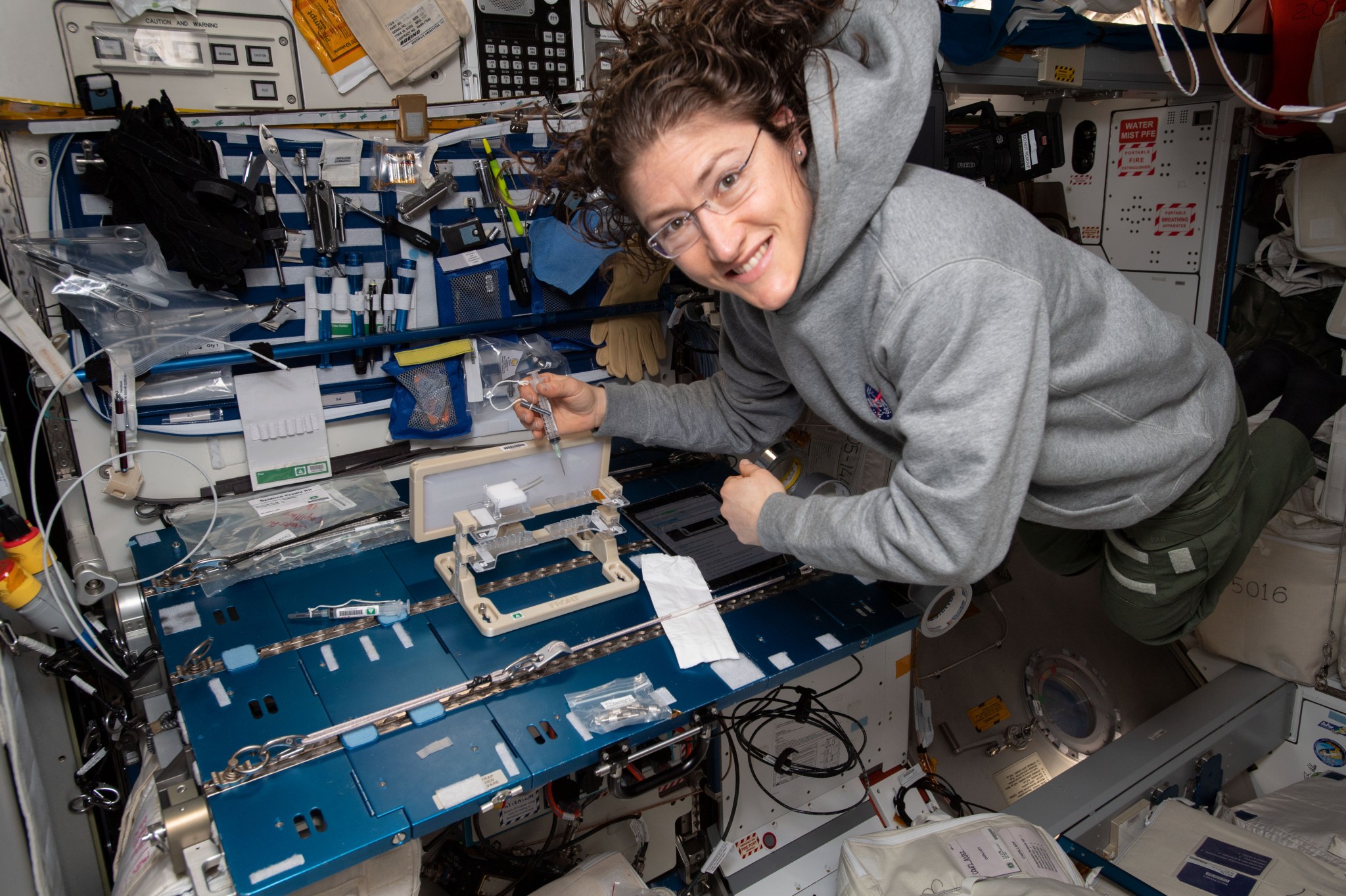 NASA astronaut Christina Koch checks out hardware for the Capillary Structures experiment.