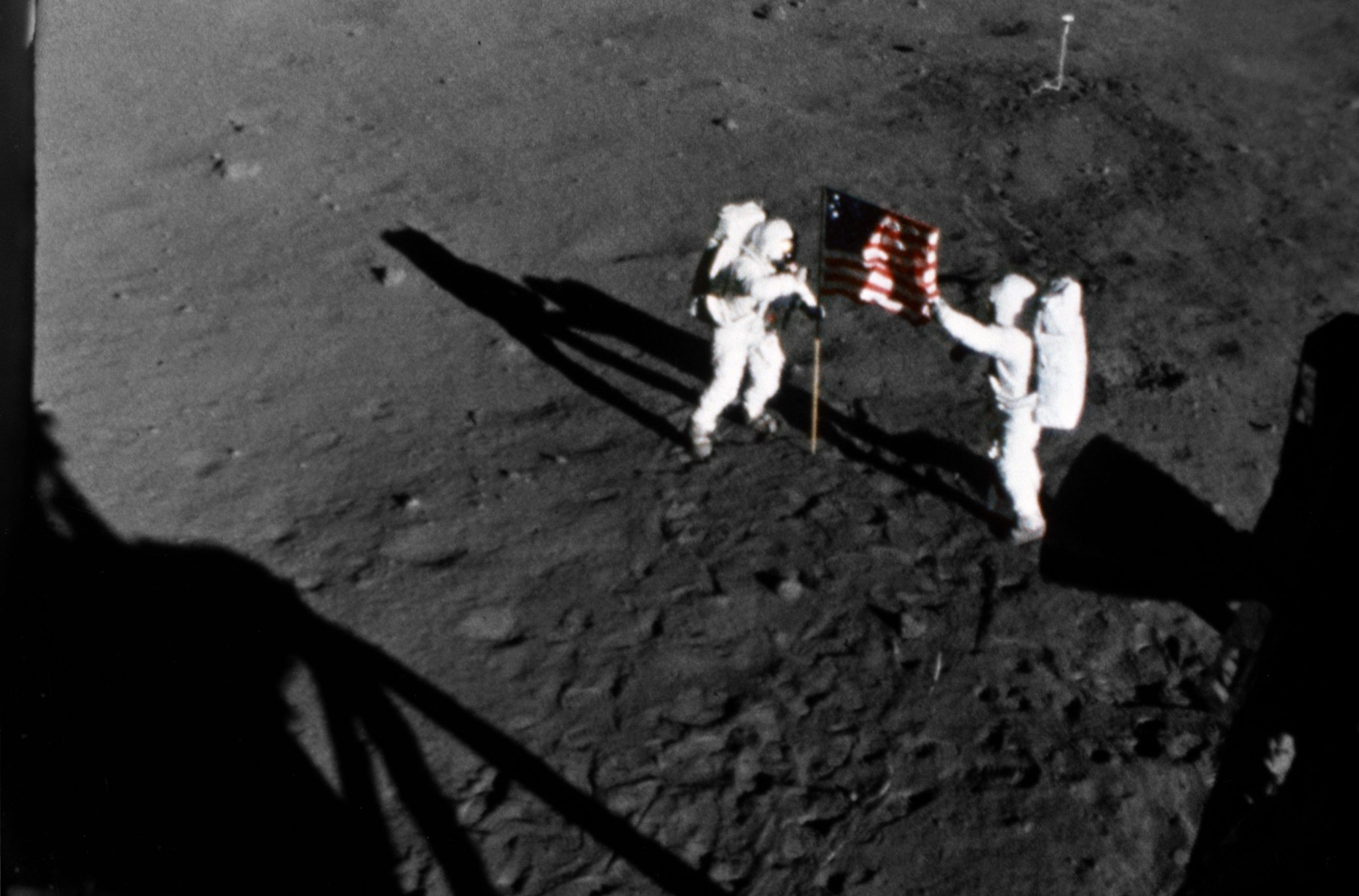 Apollo 11 astronauts Neil Armstrong and Buzz Aldrin plant a flag on the Moon.