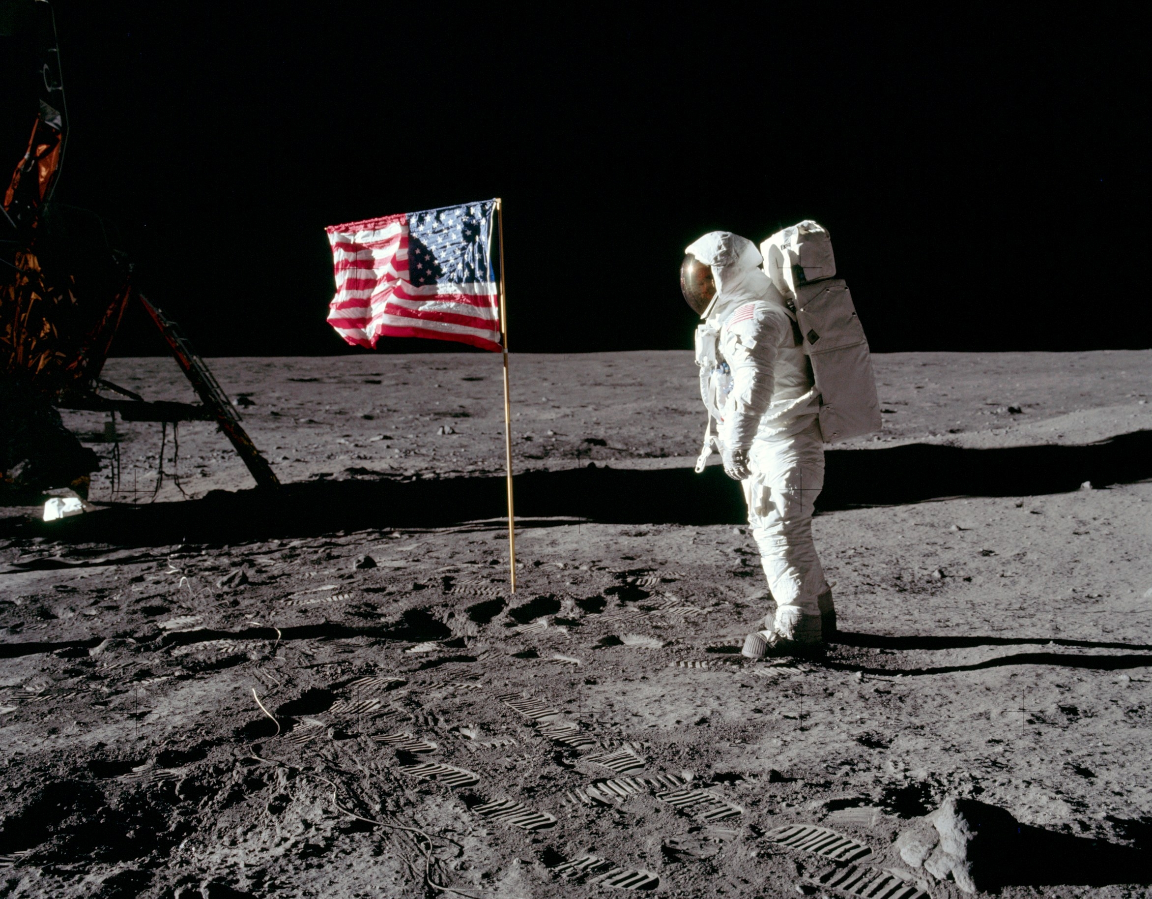 Astronaut Buzz Aldrin stands on the Moon facing a U.S. flag