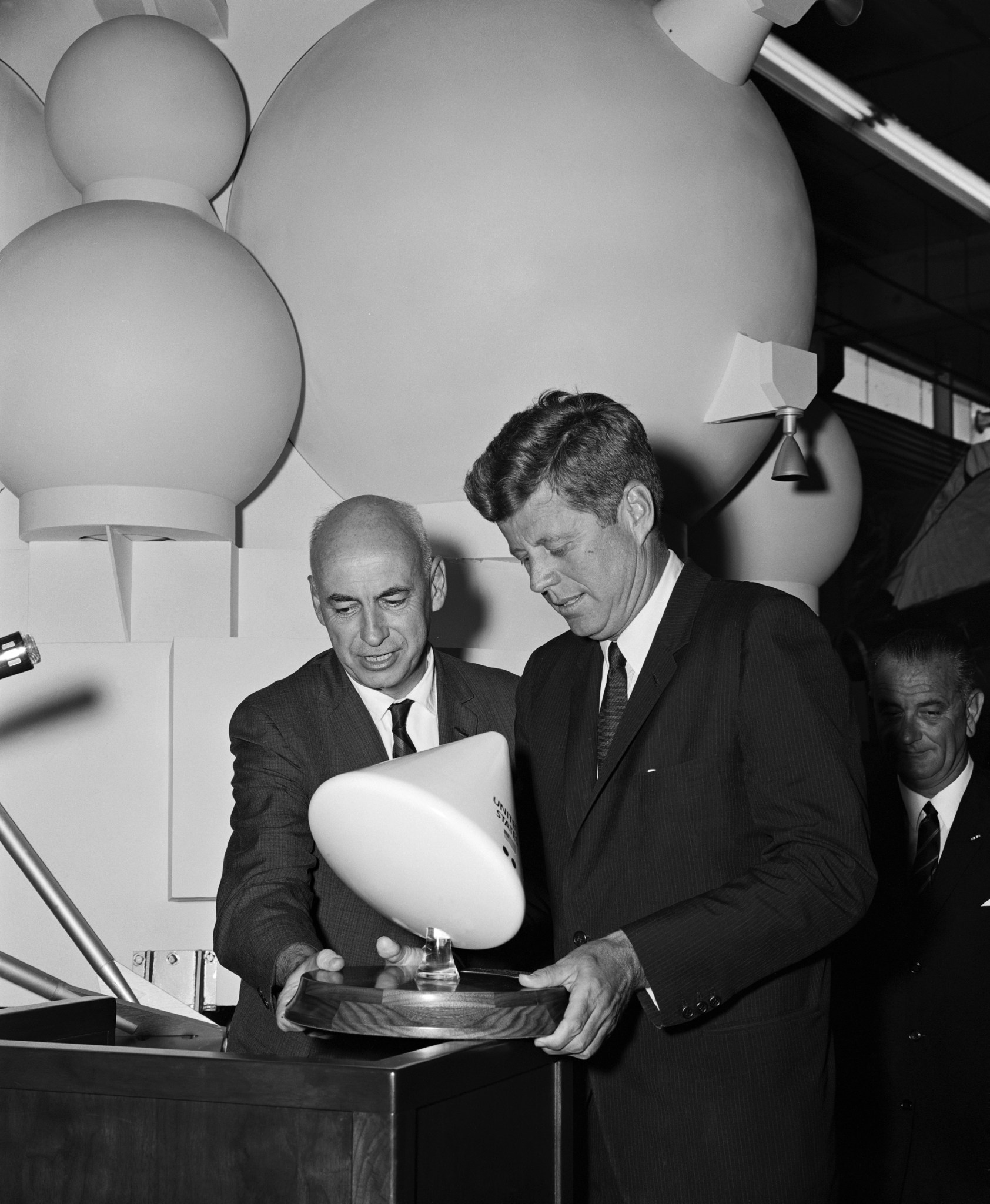 Dr. Robert R. Gilruth (left) and President John F. Kennedy look at a small model of the Apollo Command Module.