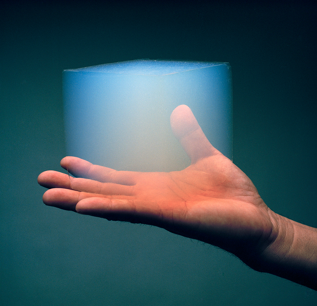 Photo of a human hand holding a cube of aerogel