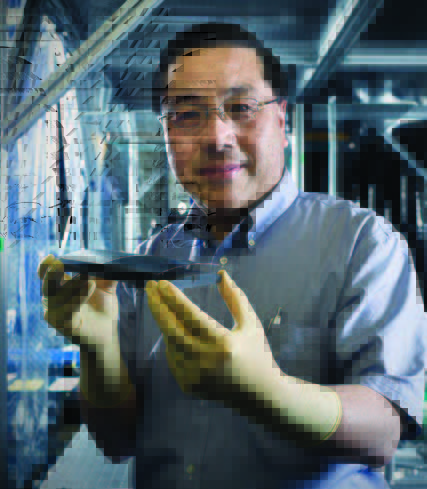 Goddard scientist Will Zhang, a man with black hair and tan skin, wears yellow gloves, glasses, and a blue short sleeved collared shirt, heholds mirror segments made of silicon. 
