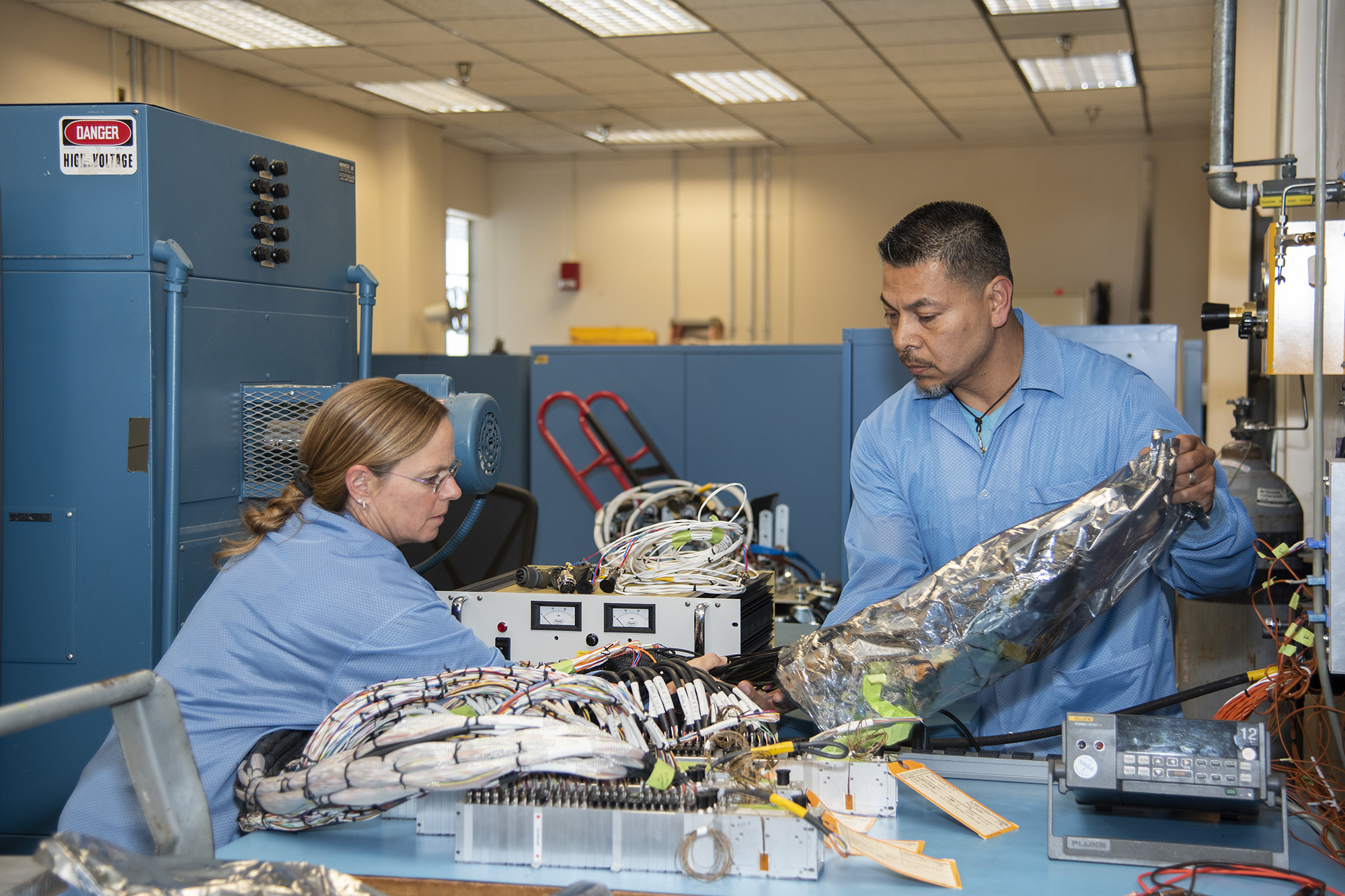 April Torres and Angelo De La Rosa remove wire harnesses for signal input for the Orion AA-2 vehicle.