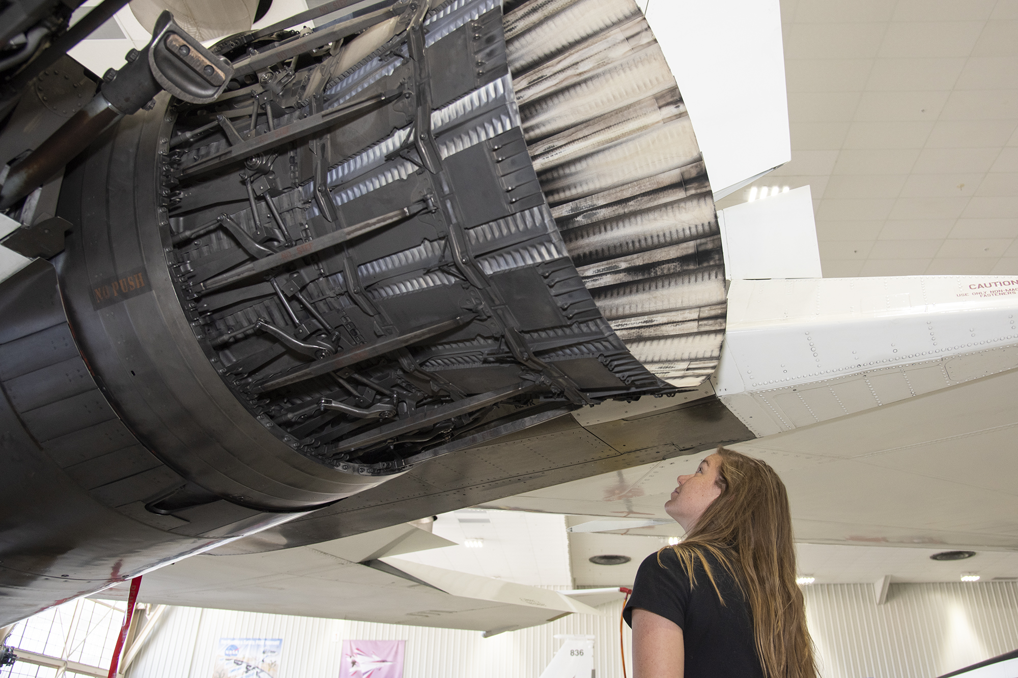 Astronaut Jenni Sidey-Gibbons looks inside the engine nozzle of an F-15 jet.