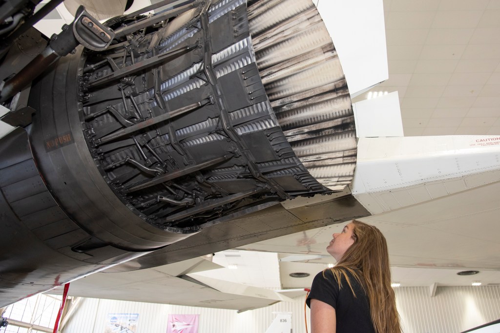 Astronaut Jenni Sidey-Gibbons looks inside the engine nozzle of an F-15 jet.