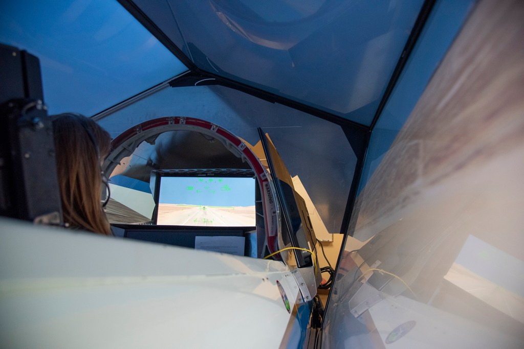 NASA's 2017 astronaut candidate Kayla Barron practices flying in an X-59 QueSST simulator at Armstrong Flight Research Center, i