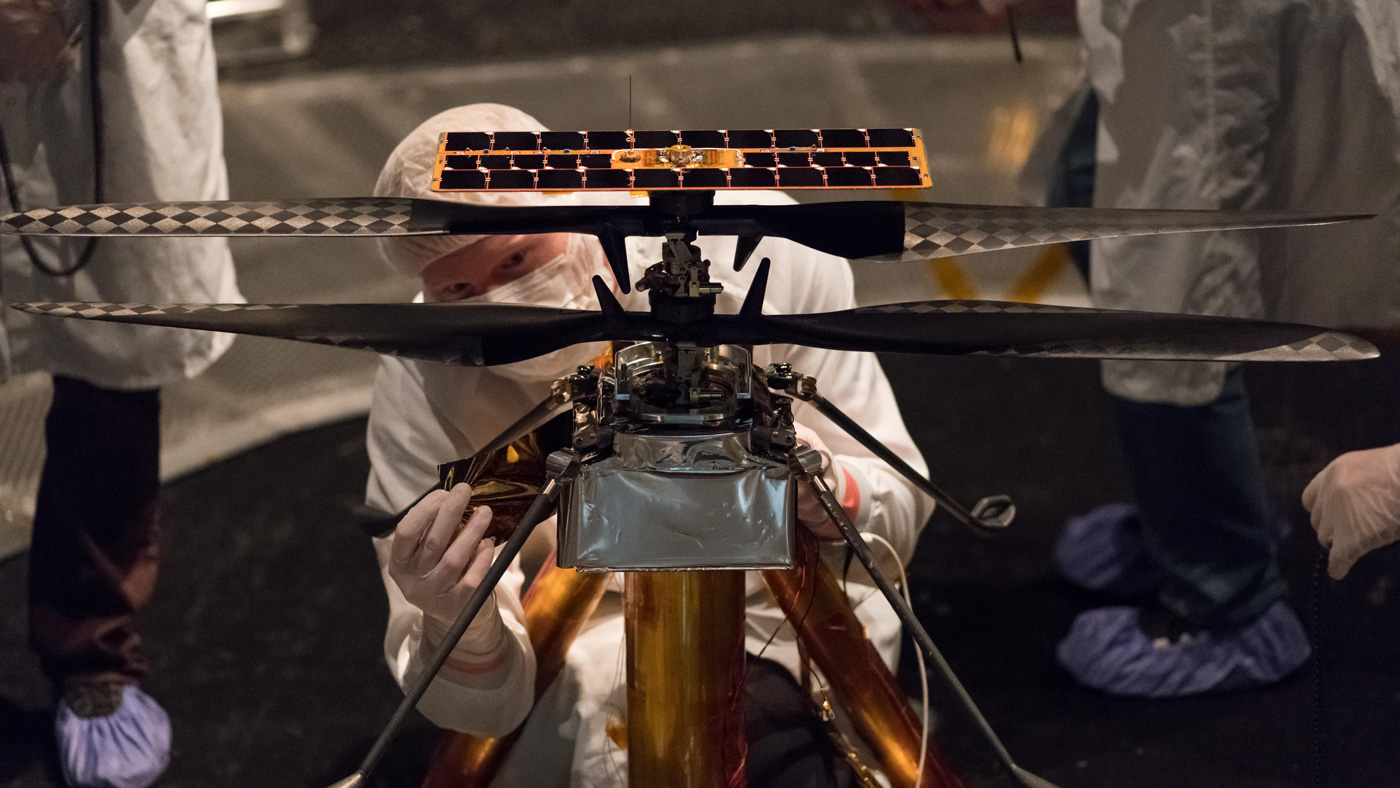 Members of the NASA Mars Helicopter team attach a thermal film to the exterior of the flight model of the Mars Helicopter