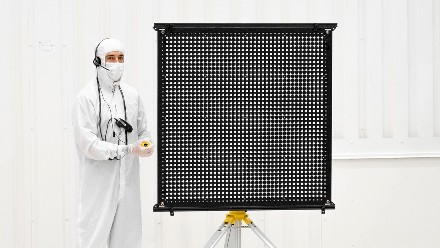 Engineer Chris Chatellier stands next to a target board with 1,600 dots.