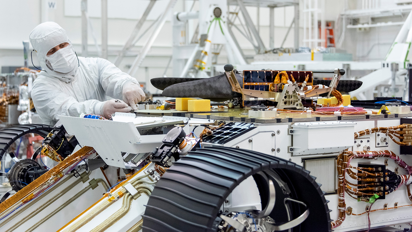 An engineer works on attaching NASA's Mars Helicopter to the belly of the Mars 2020 rover