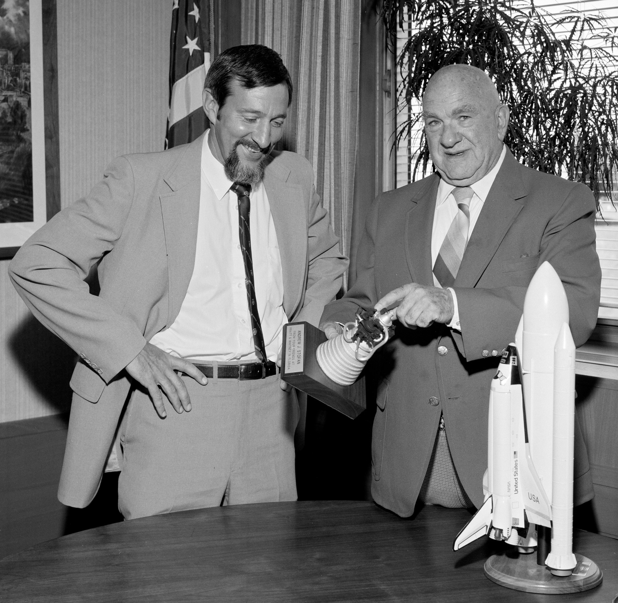 Two men with a model of a rocket engine.