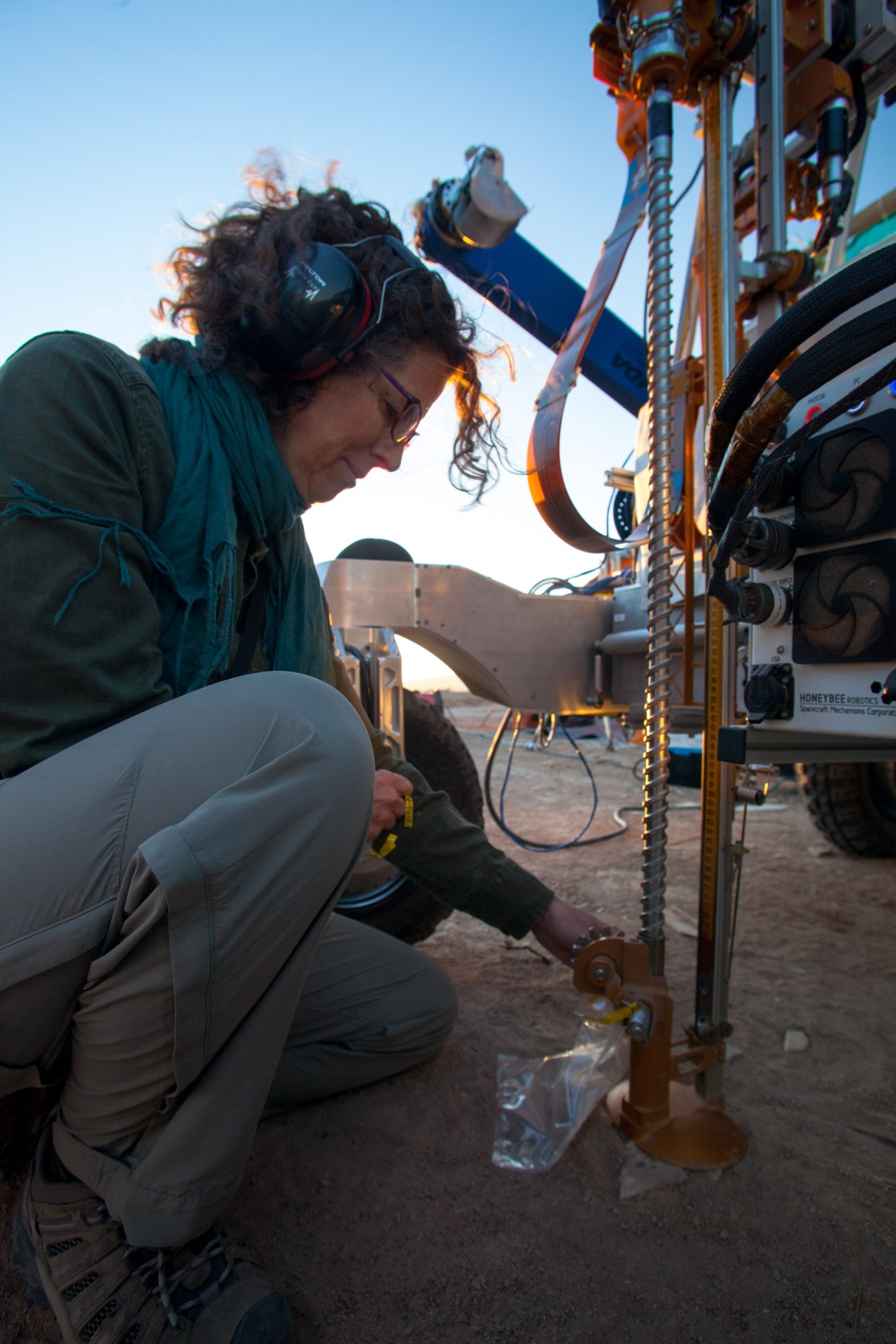 A NASA engineer inspecting the drill attached to the ARADS rover in the desert.