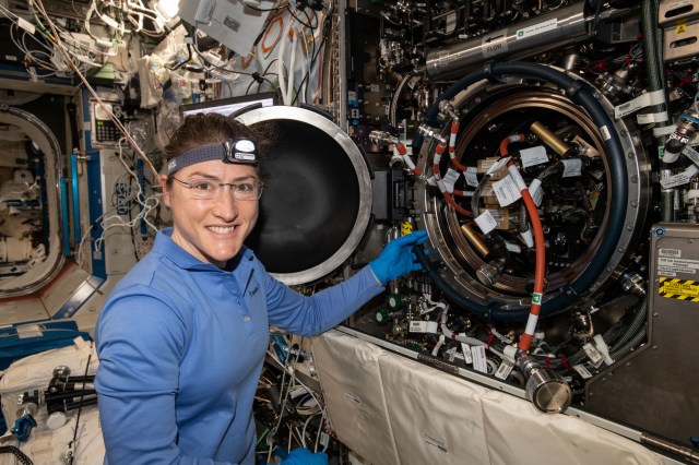 image of astronaut Christina Koch next to the Combustion Integration Rack inside the space station