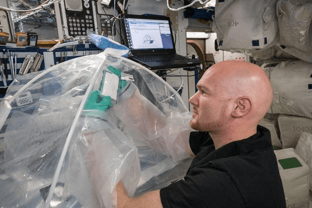 astronaut Alexander Gerst working on an experiment using a glovebox