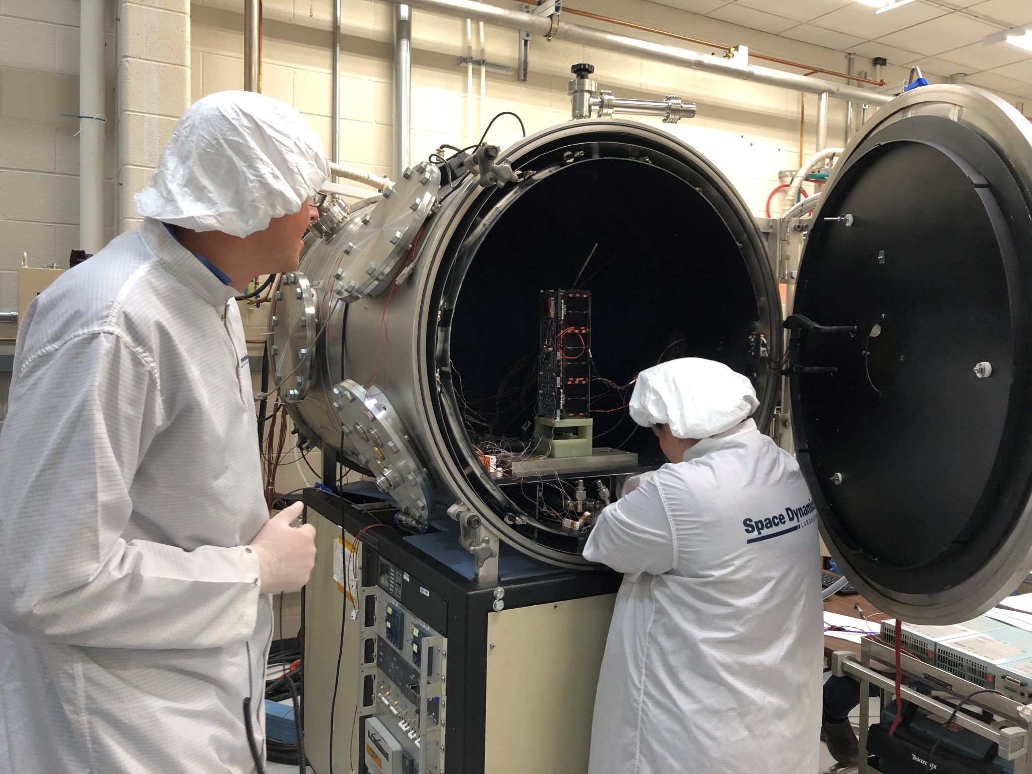 HARP Systems Engineer Ryan Martineau (left) and Thermal Vacuum Specialist Brittany Woytko configure HARP’s spacecraft in a therm