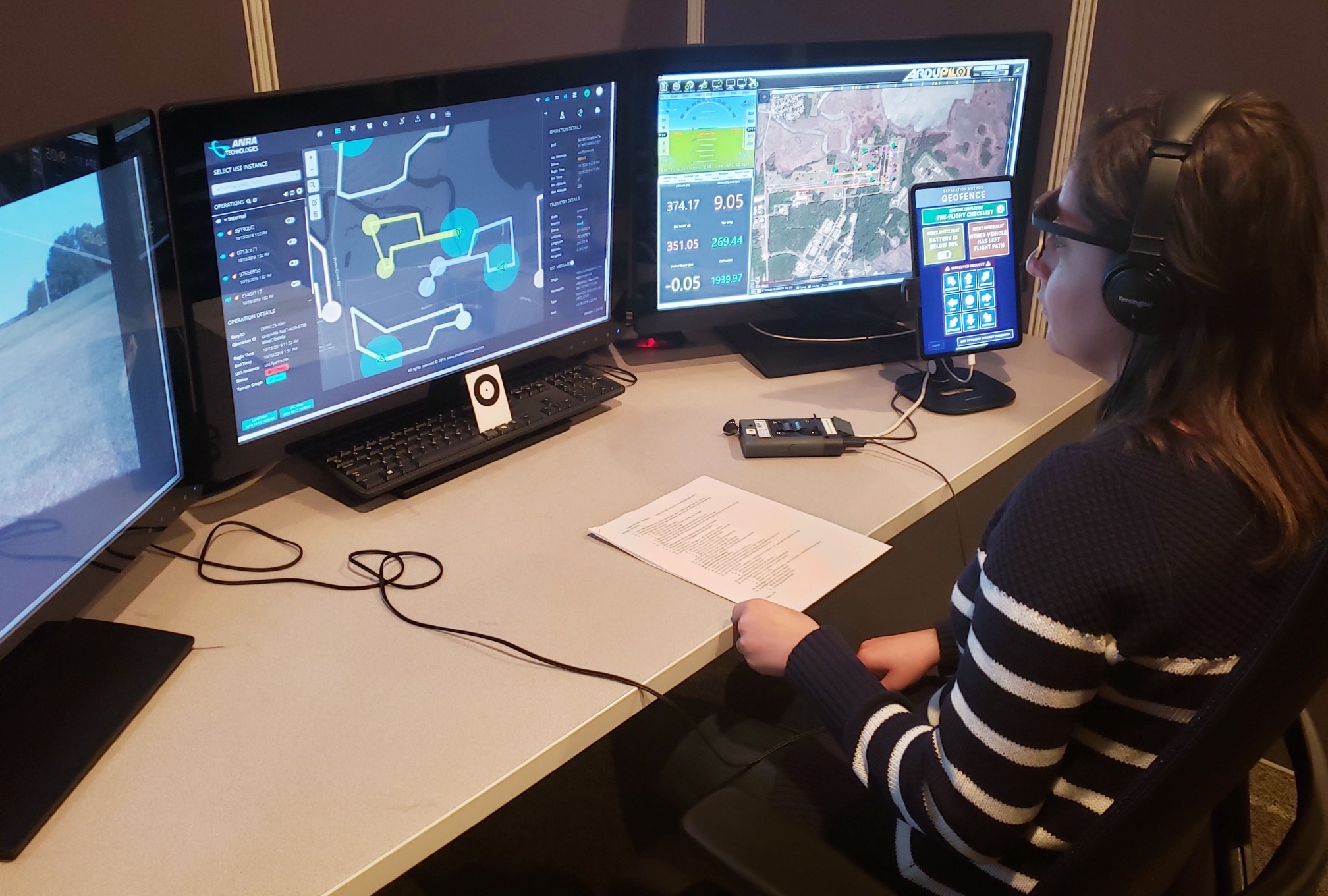 A person sitting and looking at 3 different monitors.