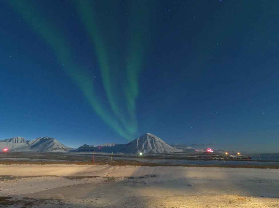 distant mountains with green streaks of aurora overhead