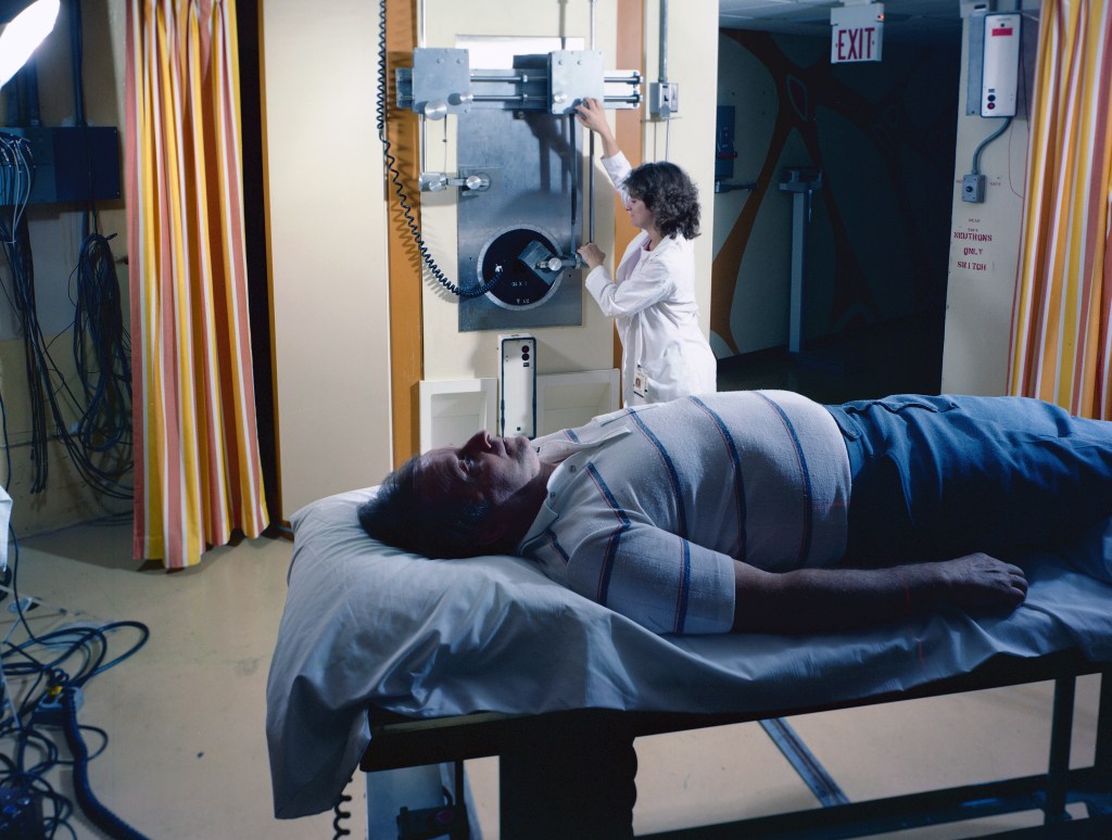 Patient lying on gurney with nurse in background.