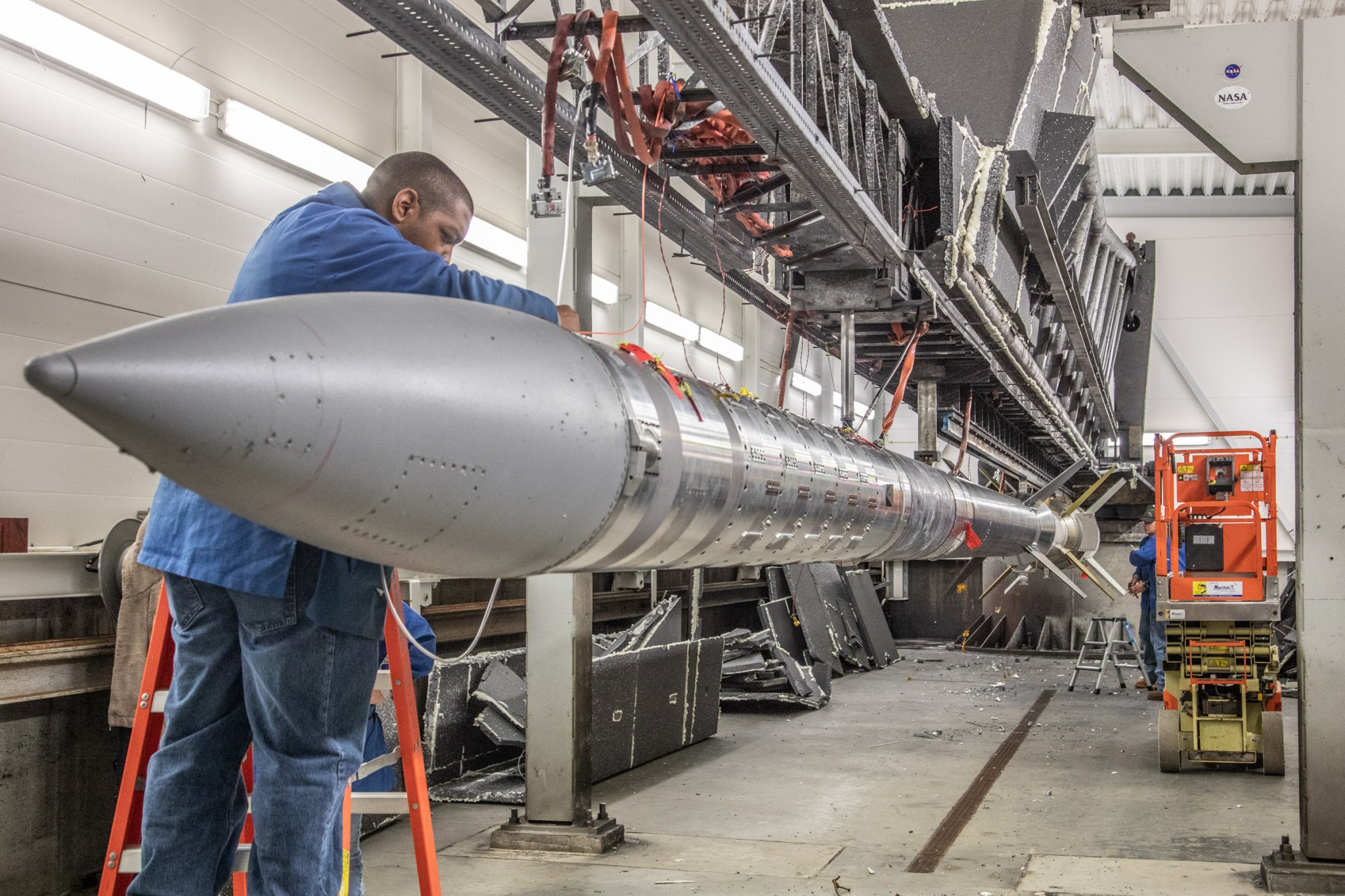 A man stands over a large silver rocket