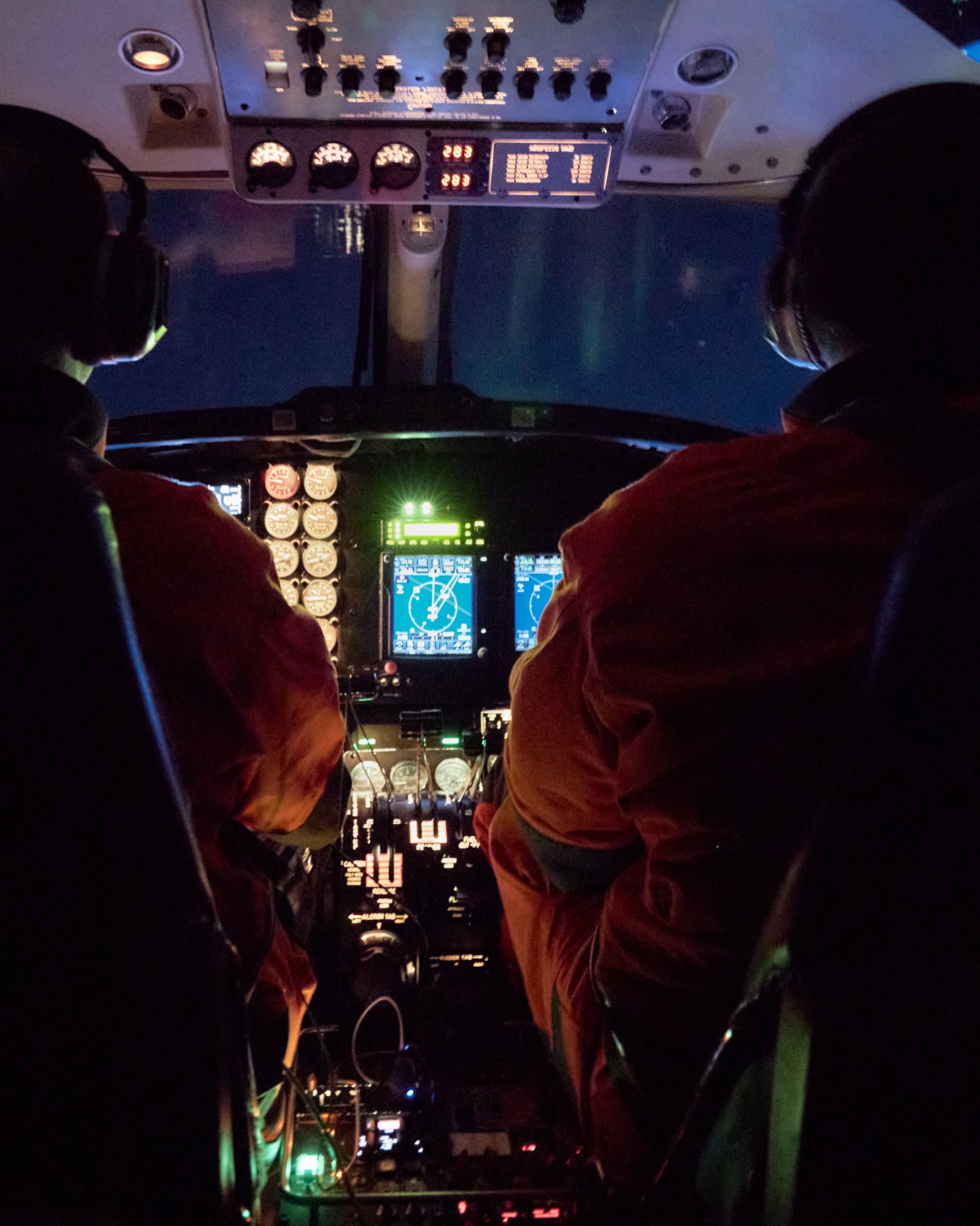 A view from aboard the B200 — green aurora visible through the window.