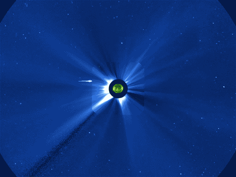A mosaic of multiple SOHO images show the Sun in green in the center against a blue background. Around the SUn a flurry of bright white dots and streaks quickly fill the view.