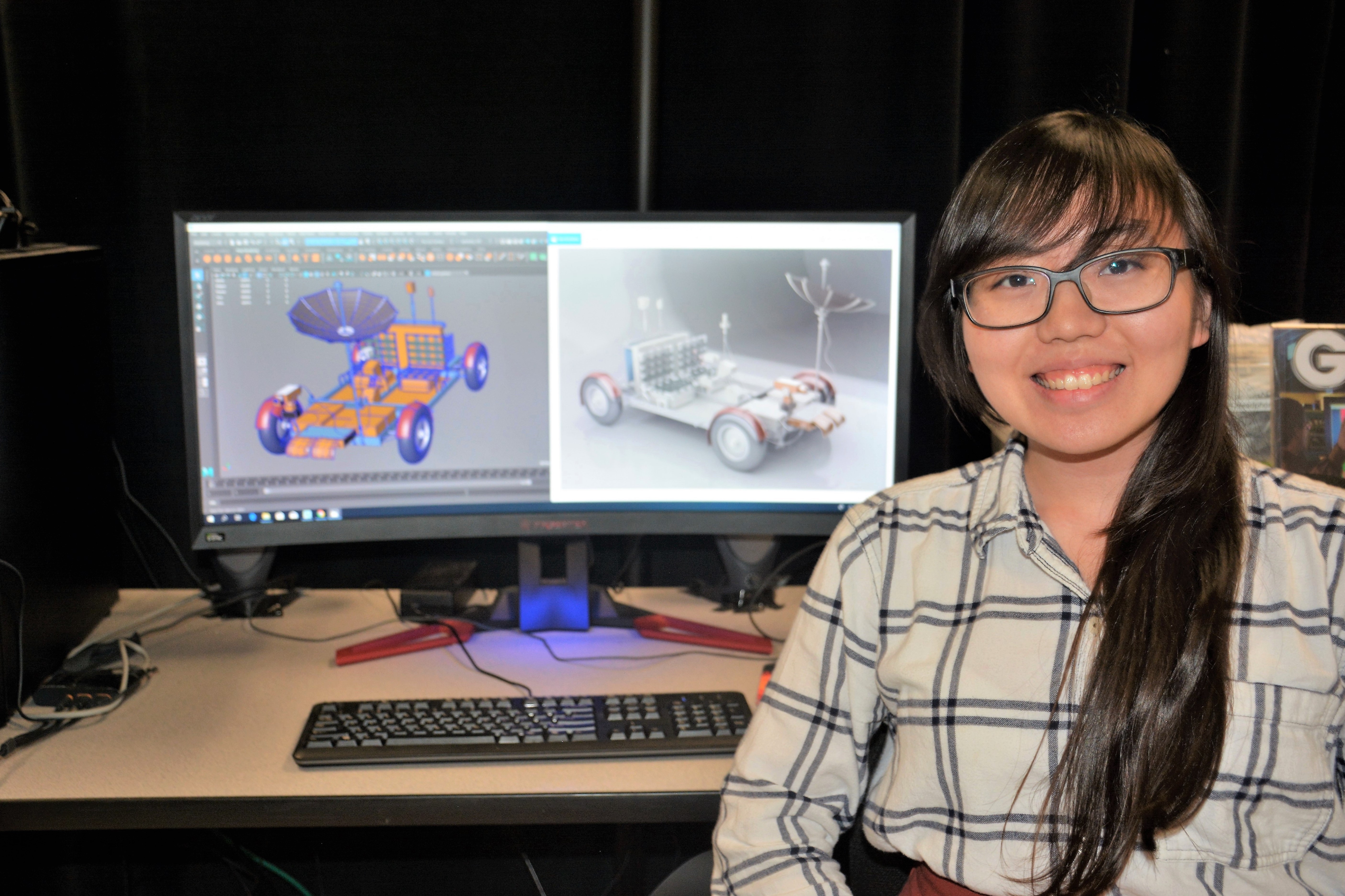 An intern sits in front of a computer displaying a 3D model of a vehicle.