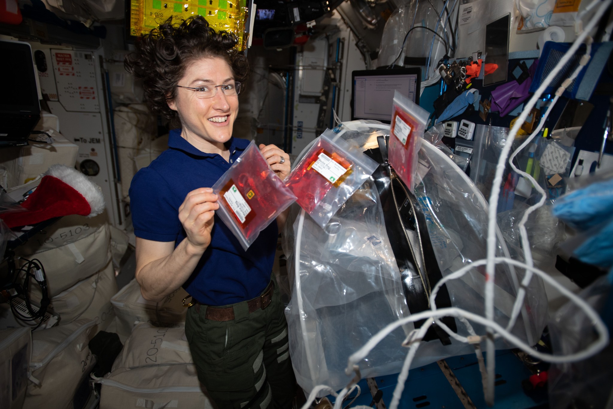 astronaut Christina Koch holding bags with 3d bioprinting material inside the space station
