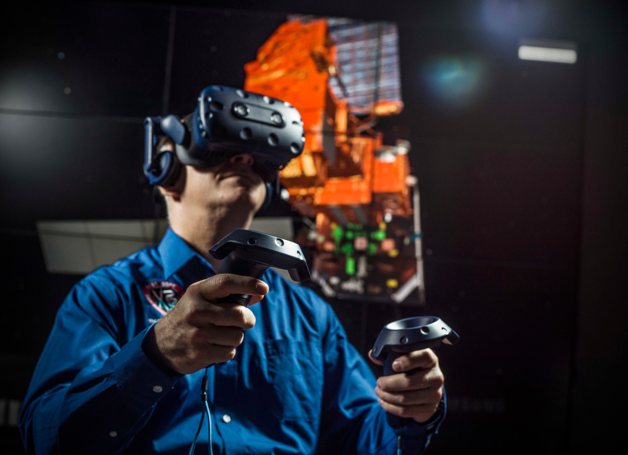 Goddard technologist Tom Grubb wearing VR goggles and holding hand controls 
