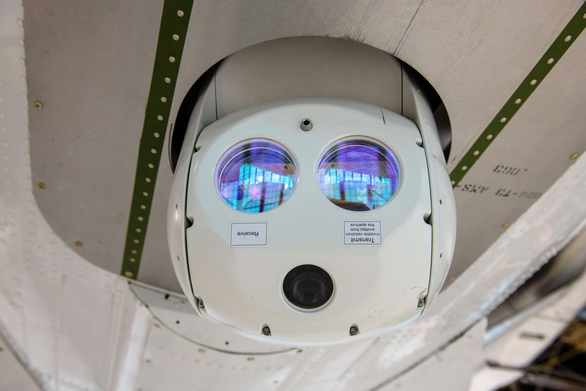A laser communication device mounted on the underside of a Twin Otter research aircraft.