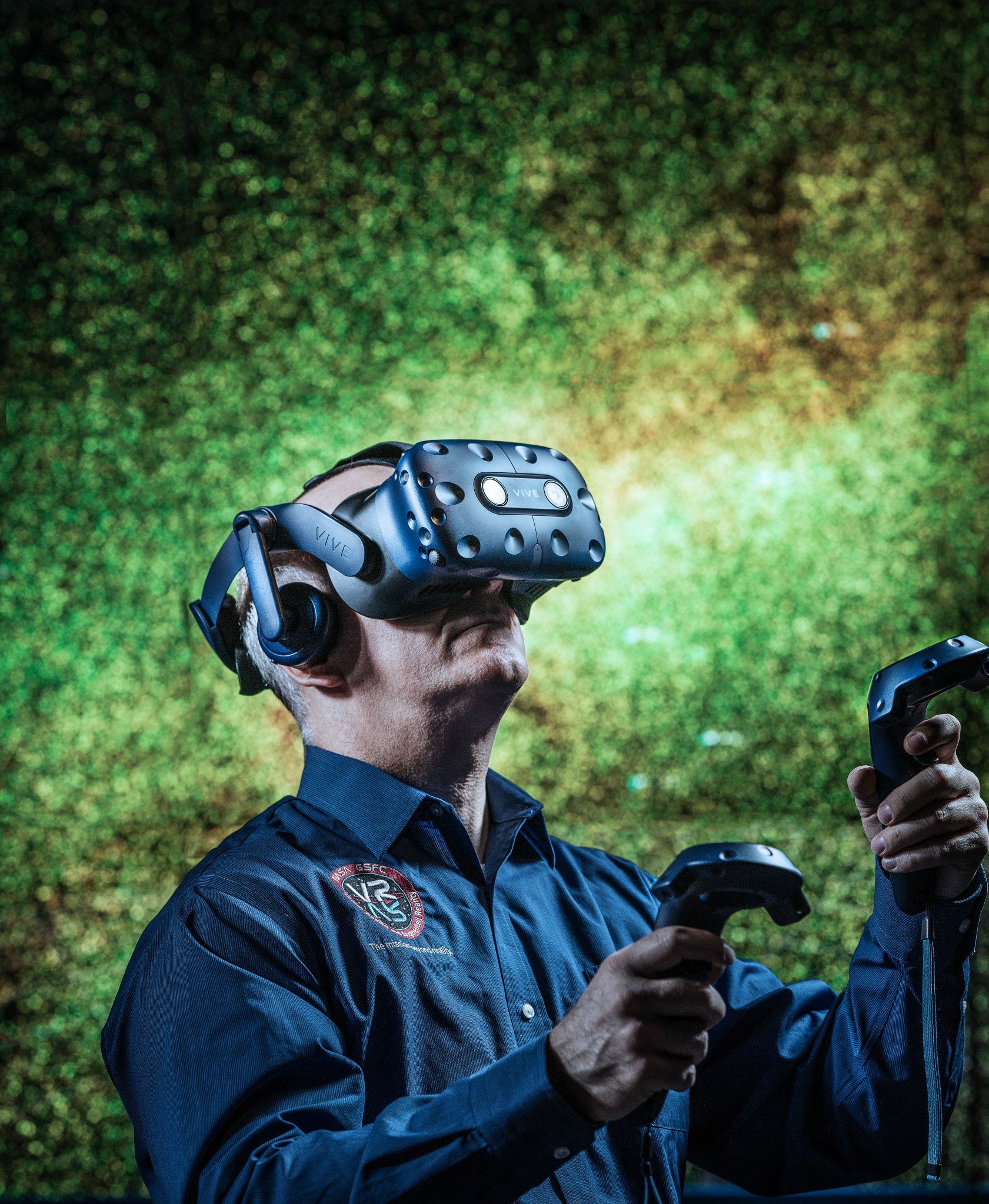 man wearing virtual reality headset in front of view of galaxy in green