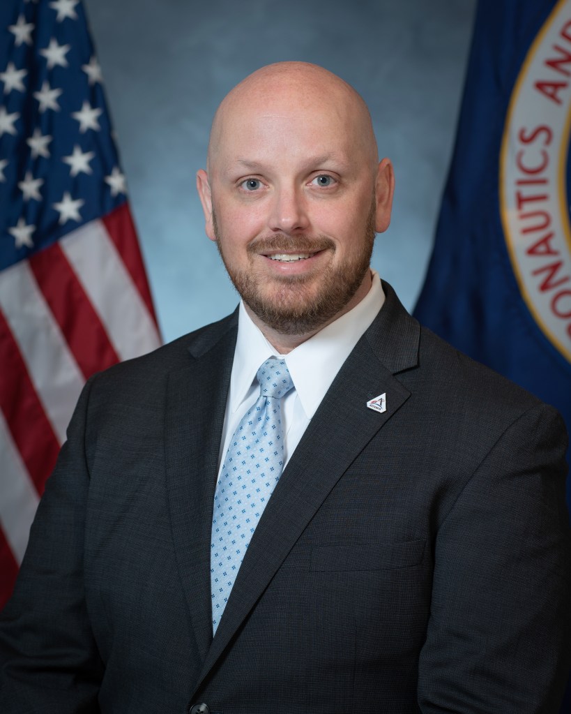 Portrait of James Jackson with U.S. and NASA Flags in background.