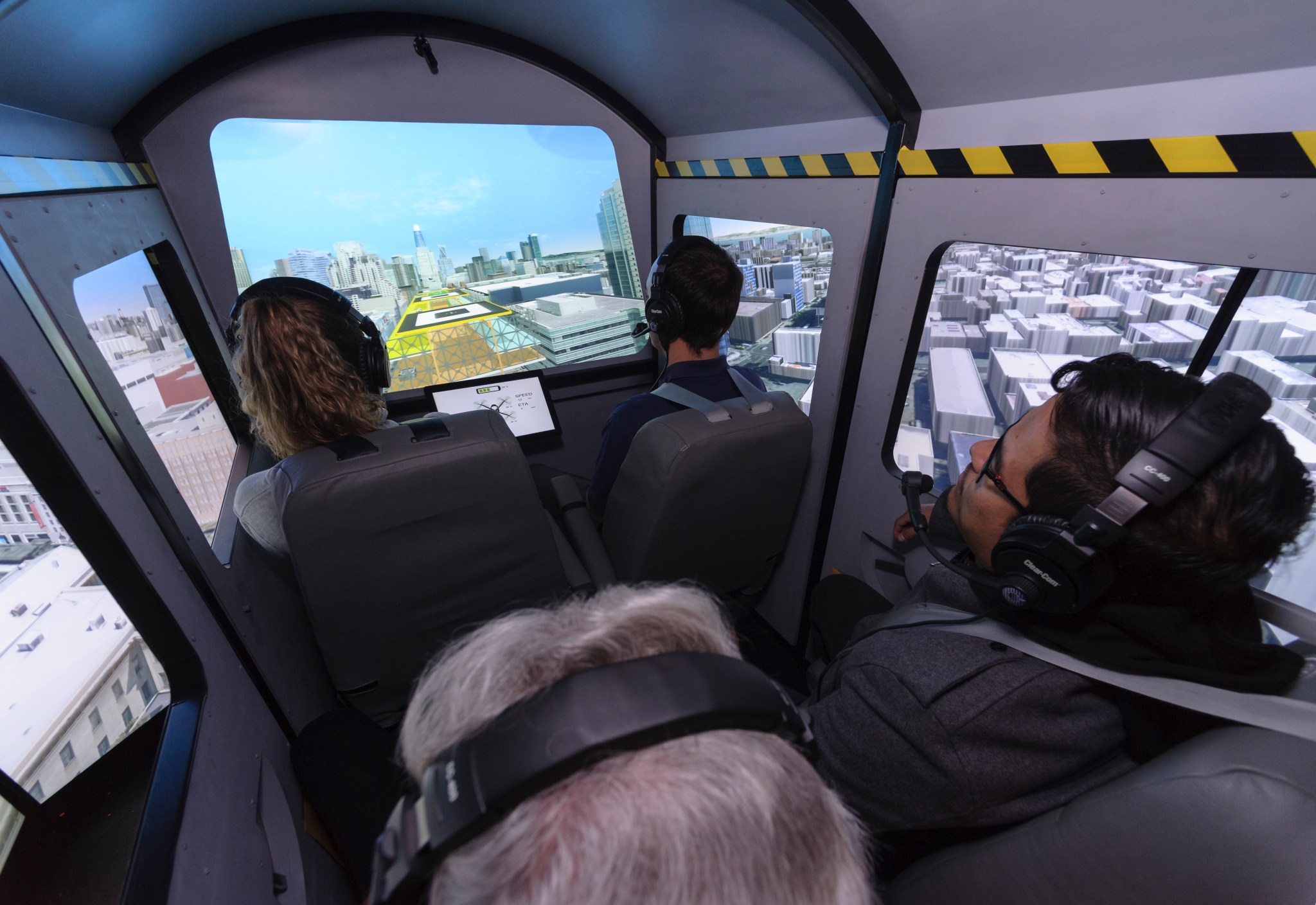 Four passengers look out the simulated windows of an air taxi cab inside the Vertical Motion Simulator at Ames.