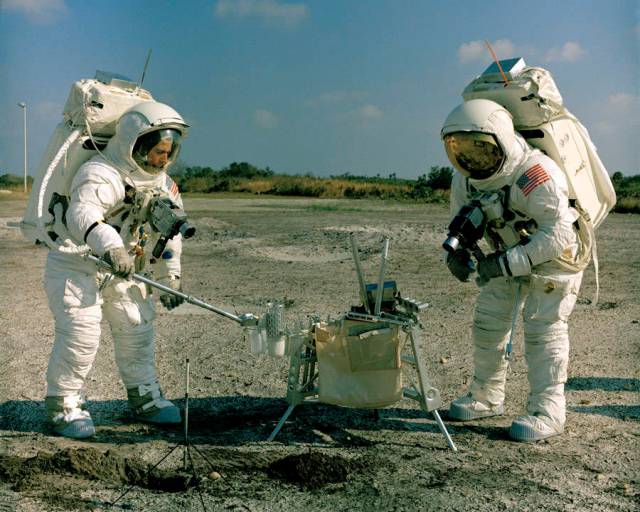 Two Apollo astronauts do lunar EVA training digging holes and collecting samples