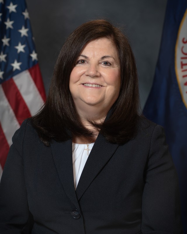 Portrait of Vicki Hagerman with U.S. and NASA Flags in background.
