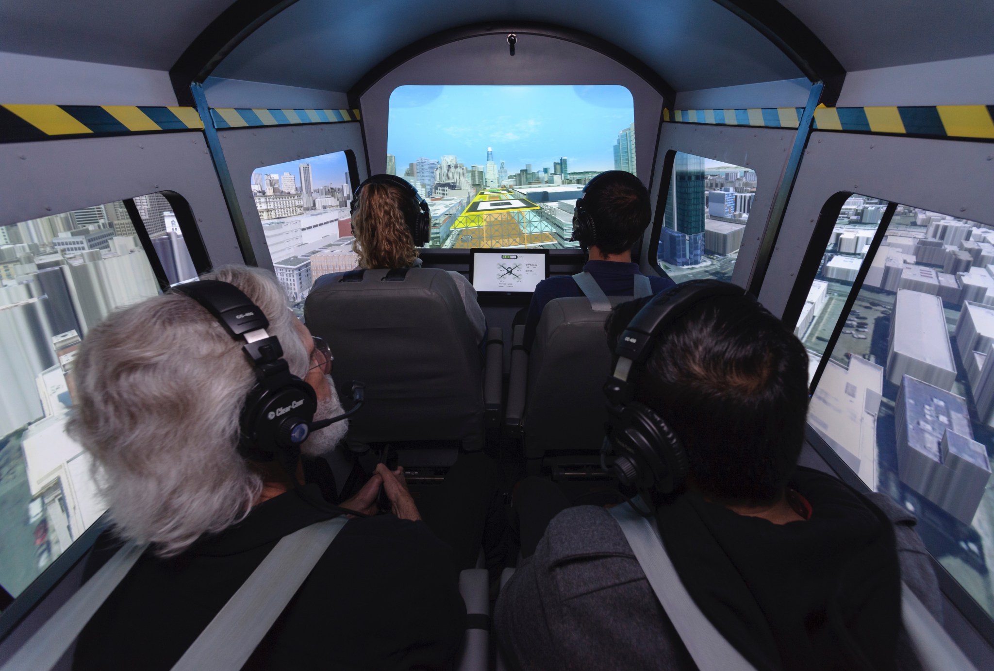 Four passengers look out the simulated windows of an air taxi cab inside the Vertical Motion Simulator
