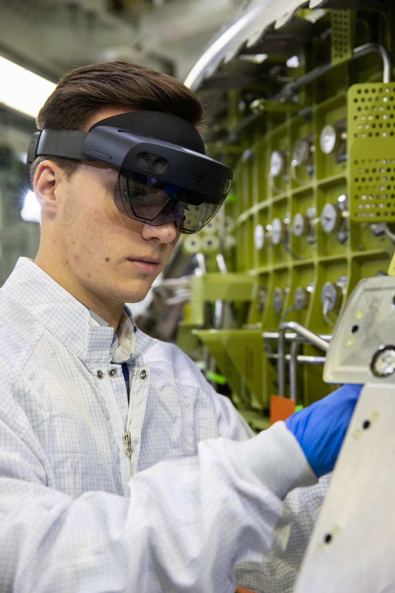 A technician wears a pair of augmented reality goggles to work on the Orion crew module for NASA's Artemis II mission.