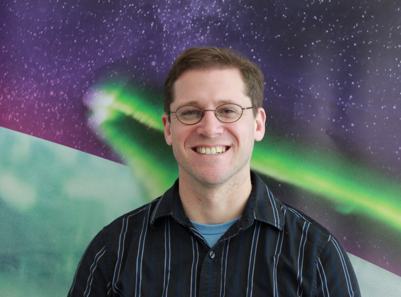 man in front of aurora image in purple and green