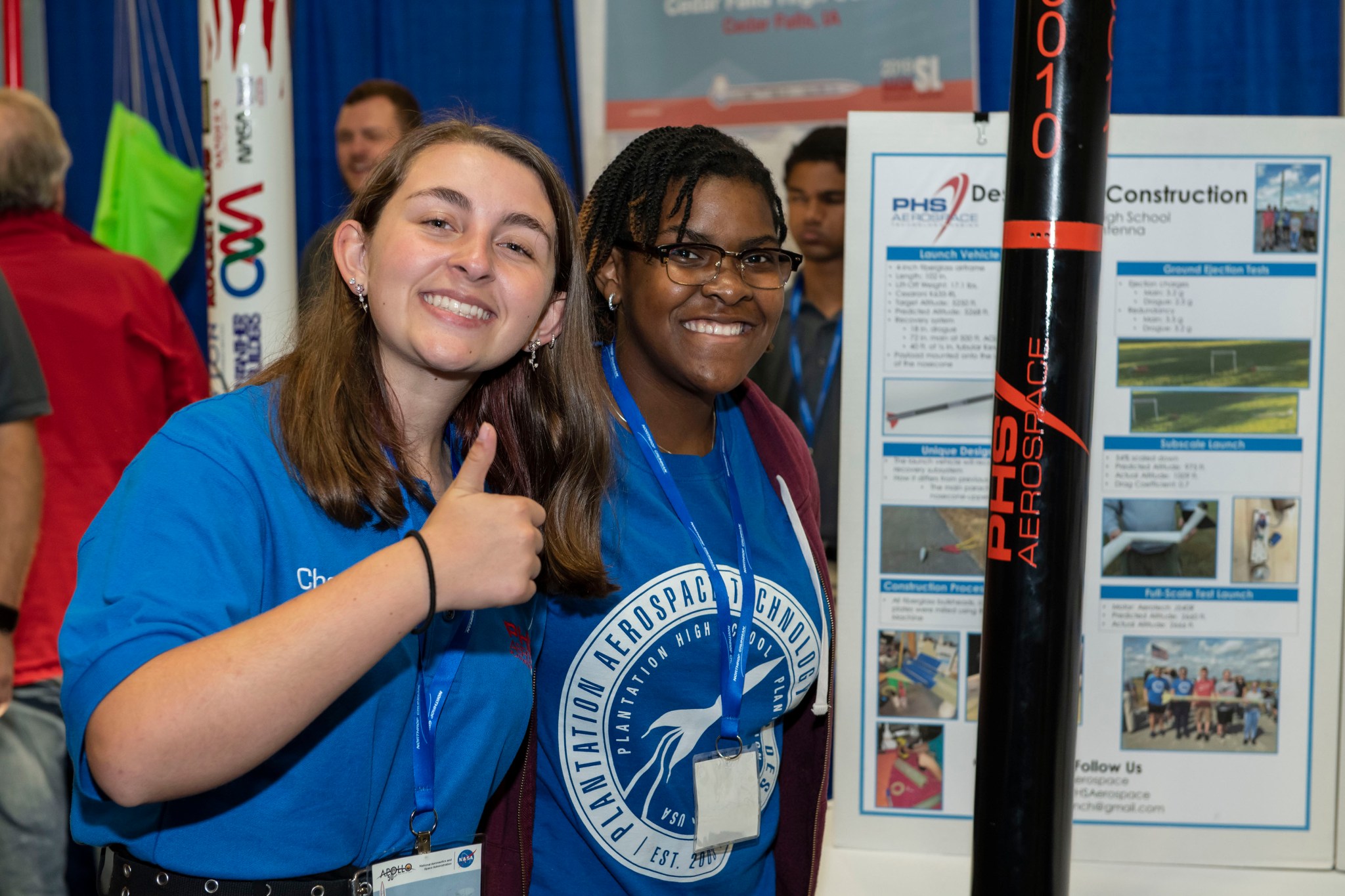 Two students standing next to exhibit giving a thumbs up