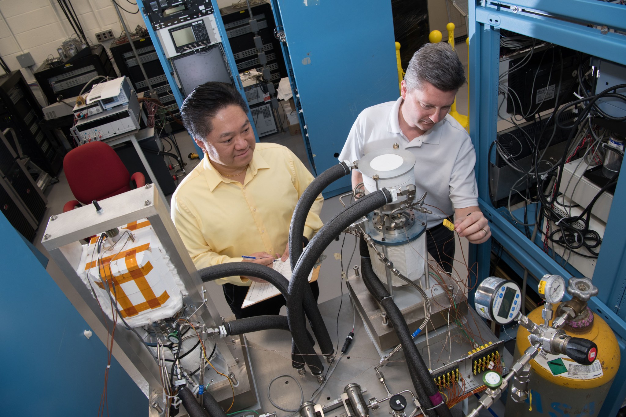 Two researchers stand in a lab examining the model of a power generator.
