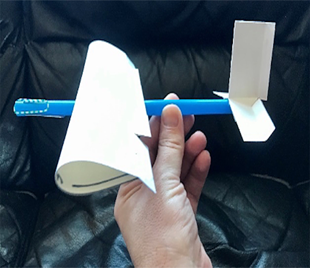 Hand holds airplane made from a straw and paper