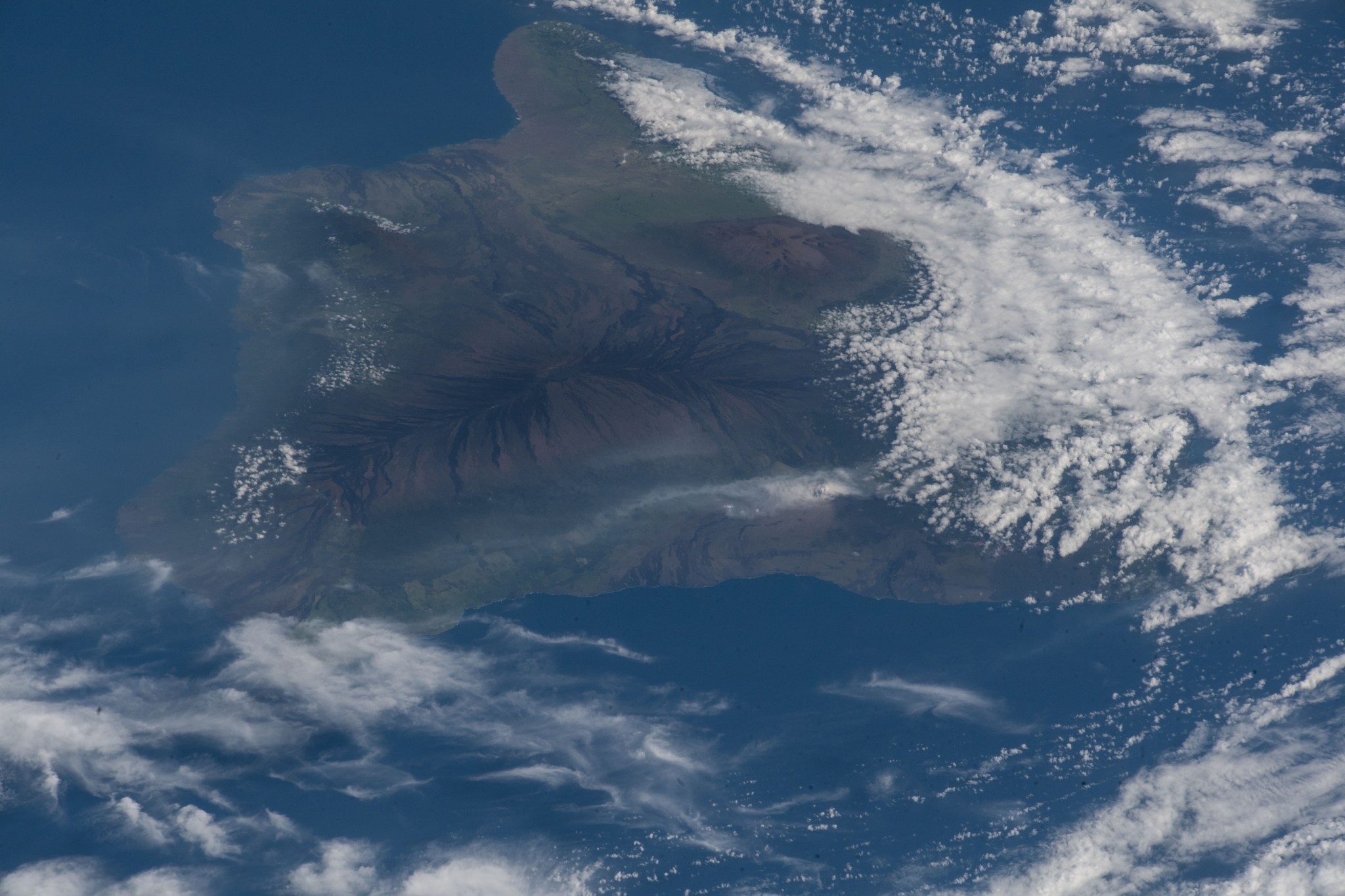 The ash plume from the Kilauea volcano on the big island of Hawaii was pictured May 12, 2018, from the International Space Station. The ash is gray over the green and brown landmass, all surrounded by bright blue water.